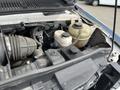 Close-up of the engine compartment of a 2009 Ford Econoline showing components like the air intake hose coolant reservoir and various tubes and connections