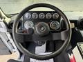 Interior view of a 2010 Autocar Xpeditor's dashboard featuring a round steering wheel several gauges and a textured floor mat