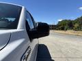 A 2016 Ford F-150 parked with a focus on its side mirror and part of the front. The truck is white with a sleek design