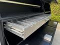 A set of metal storage drawers inside a compartment of a 2016 Ford F-550 with multiple sliding sections for organizing tools or equipment