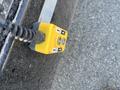 A yellow control panel with two buttons and a coiled cord, used for operating machinery, sitting on a textured surface