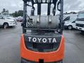 A 2011 Toyota 028FG15 forklift with a large propane tank mounted on the back and the Toyota logo prominently displayed on the front