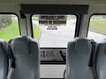 Interior view of a 2016 International CE300 bus showing gray seats and an emergency door sign on the back wall