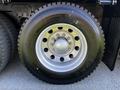 A close-up of a silver alloy wheel with a black tire labeled Firestone mounted on a Freightliner M2 112 truck