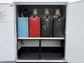 A compartment containing four fuel tanks in various colors including blue red and black with labeled dispensers