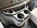 A close-up of a gray console in a 2022 Ford E-450 featuring two cup holders and control buttons for air conditioning and heating