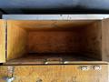 An empty wooden storage compartment with an open lid and visible wooden interior showing signs of use and wear