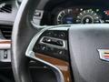 Close-up of the steering wheel controls of a 2016 Cadillac Escalade featuring buttons for cruise control and a wood grain accent