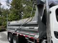A 2010 Freightliner M2 106 dump truck with a metallic bed and rear hydraulic system is shown from the side angle