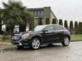 A 2016 Mercedes-Benz GLA-250 parked on a wet surface featuring a sleek black exterior and distinctive front grille with the Mercedes logo