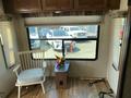 A 2016 Jayco 265RLSW with a cozy interior featuring a white wooden chair and a small table decorated with a colorful star ornament