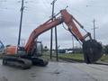 A 2006 Hitachi ZX200LC excavator with an orange arm and large digging bucket raised above the ground