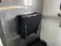 A black folding seat mounted on a metallic wall inside a vehicle