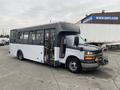 A 2017 Chevrolet Express bus with a black and white exterior is parked with its doors open and a bumper guard attached at the front