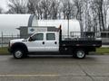 A 2015 Ford F-550 truck with a flatbed design and mounted equipment on the side