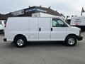 A 2012 GMC Savana van with a plain white exterior and a sliding side door parked with its wheels visible and a simple design