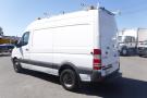 A white 2012 Mercedes-Benz Sprinter van with a high roof and roof-mounted equipment holders parked in an outdoor setting