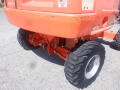 2008 JLG Boom Lift with large rubber wheels visible in the foreground and orange body showcasing signs of wear and tear