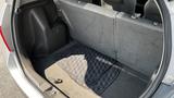 The interior of a 2006 Honda Fit with folded rear seats and a gray carpet mat on the floor