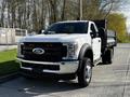 A 2018 Ford F-550 truck in white with a black dump bed, featuring a chrome grille and prominent headlights