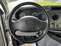 The steering wheel of a 2013 Ford Econoline with a black textured surface and the Ford logo in the center