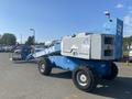 A blue 1997 Genie S-65 4X4 aerial lift with large tires and a platform on an extendable arm for reaching high places