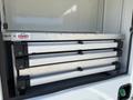 A set of three collapsible aluminum ramps stored in a compartment of a 2023 Ford F-550 vehicle