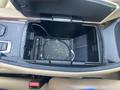 A 2009 BMW X5's center console with an open compartment showing debris and a black charging cable inside