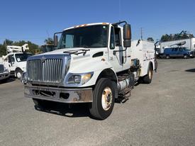 A white 2007 International 7300 truck with a flatbed and utility box attached to the side