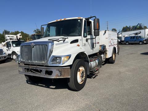 A white 2007 International 7300 truck with a flatbed and utility box attached to the side