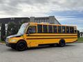 A yellow 2022 Freightliner B2 school bus with black stripes parked at an angle showcasing its large windows and dome lights