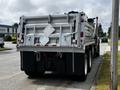 A 2017 International WorkStar 7600 dump truck with a silver cargo bed and reflective diamond warning signs on the rear