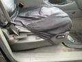 A 2004 Ford Explorer Sport Trac driver's seat covered with a black seat cover showing signs of wear