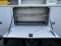 A 2008 Ford F-550 with an open storage compartment revealing two metal shelves and a white surface inside