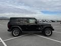 A 2019 Jeep Wrangler in black parked in a lot featuring a four-door design large tires and the Jeep logo on the side