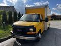 A yellow 2017 GMC Savana cargo van with a silver box cargo area parked in a lot