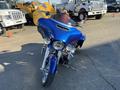 A 2017 Harley-Davidson FLHXS in a shiny blue color featuring a large fairing dual headlights and chrome accents