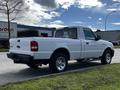 A white 2010 Ford Ranger pickup truck parked on the street with a single cab and chrome wheels