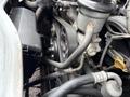 Close-up of the engine components of a 2009 Toyota Hiace featuring belts and pulleys with various hoses and connectors