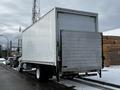 A 2019 Hino 338 24-foot cube truck with a white exterior and a rear liftgate parked on the side of the street