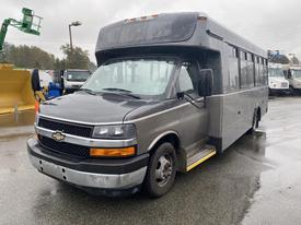 A 2017 Chevrolet Express bus in gray with a black front bumper and large windows on the side