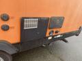 2015 Winnebago of Indiana travel trailer with an orange exterior featuring various hookups and a vent on the side