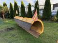 A yellow snow plow blade mounted on a grassy area with red flags attached to the sides