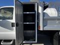 A 2008 Ford F-450 SD with an open storage compartment featuring metal shelves inside