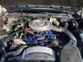 The engine compartment of a 1982 Mercury Grand Marquis featuring a large air intake manifold various hoses and wires along with a caution fan label