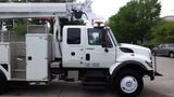 A white 2012 International 7400 truck with a bucket lift mounted on the side and various tool compartments visible