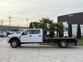A 2020 Ford F-550 in white with a flatbed design parked at an angle showcasing its side profile