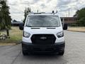 Front view of a 2023 Ford Transit van in white with a black grille and roof rack