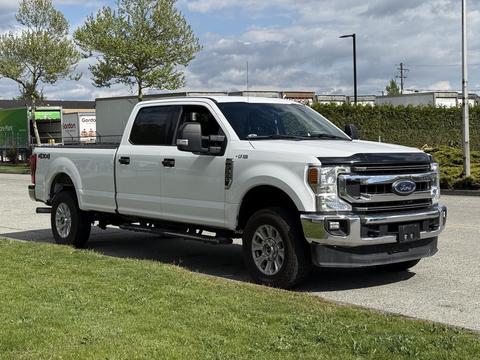 A 2020 Ford F-350 Super Duty pickup truck in white with a crew cab and chrome accents parked on a grassy area