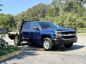 A blue 2017 Chevrolet Silverado 1500 pickup truck with a flatbed attachment parked on a paved surface